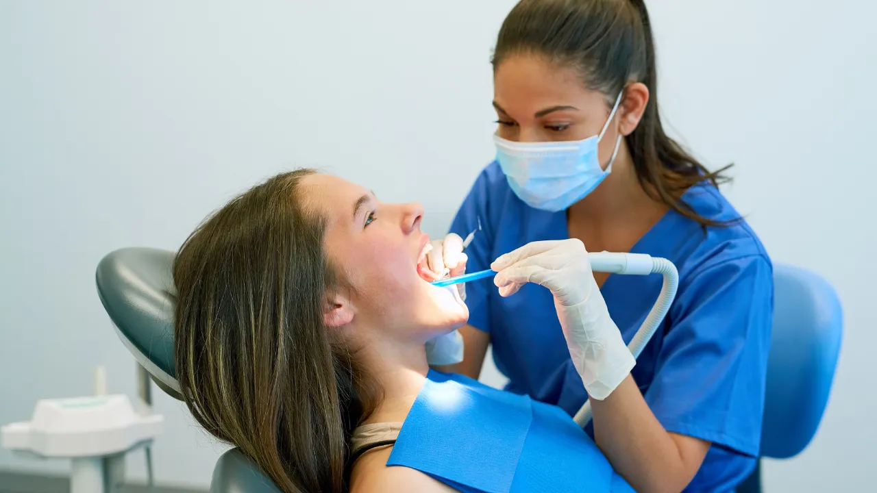 A dentist examining a patient’s teeth after wisdom teeth removal, representing the importance of following the complete list of soft foods for safe recovery.